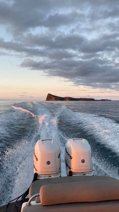 two seats on the back of a boat traveling through the ocean at sunset or dawn