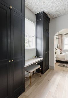 a bedroom with black cabinets and a white bed in the background, along with hardwood floors