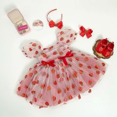 the doll is wearing a pink dress with strawberrys on it