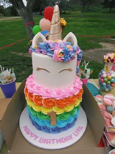 a birthday cake in the shape of a unicorn with rainbow icing and decorations on top