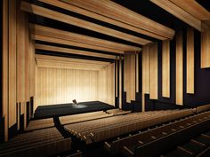 an empty auditorium with wooden walls and benches