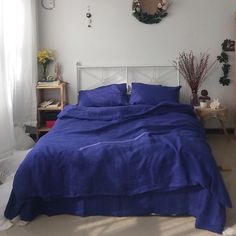 a bed with blue sheets and pillows in a room next to a clock on the wall