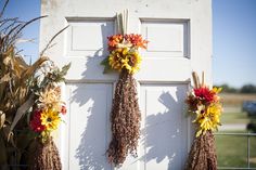 three dried flowers hang from the side of a white door