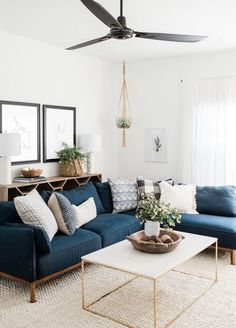 a living room with blue couches and white rugs on the floor in front of two windows