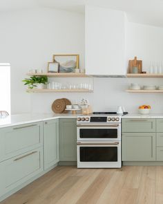 a white stove top oven sitting inside of a kitchen next to wooden floored floors