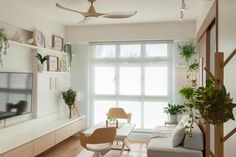 a living room filled with furniture and a flat screen tv mounted to a wall next to a window