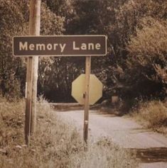 an old photo of a road sign and stop sign on the side of a dirt road