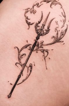 a tattoo on the back of a woman's thigh with an arrow and swirls