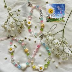 some flowers and beads on a white table with a card next to it, along with an image of a smiling face