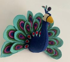 a blue and green stuffed peacock on a white surface