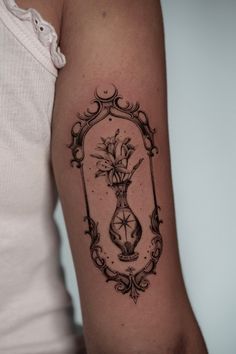 a woman's arm with a tattoo on it that has flowers in a vase