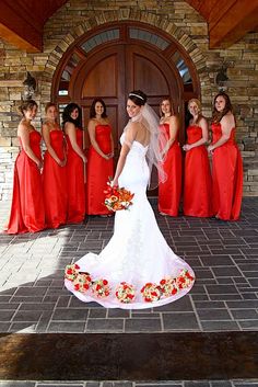 a bride and her bridal party in front of a church door wearing red dresses