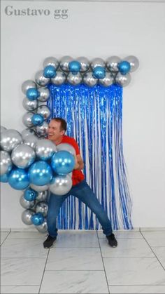 a man standing in front of a blue and silver balloon arch