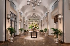 an elegant hallway with potted plants and chandeliers