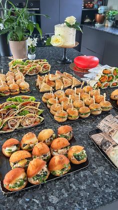 many sandwiches are arranged on trays with toothpicks in the middle, along with other food items