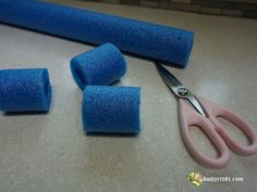 some blue sponges and scissors on a table with one pair of pink handled scissors