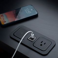 an iphone plugged in to a charger on top of a table next to a phone