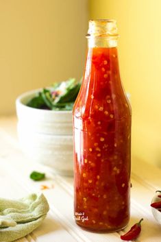 a bottle filled with ketchup sitting on top of a table next to a bowl