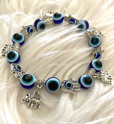 Beautiful handmade evil eye bracelet. Beaded with various charms. Stretchy band. Evil Eye Charm Bracelet, Blue Charm Bracelet, Handmade Blue Bohemian Charm Bracelet, Adjustable Charms Bracelets For Festival, Handmade Blue Evil Eye Bracelet For Festival, Handmade Bohemian Blue Evil Eye Bracelet, Handmade Blue Bohemian Evil Eye Bracelet, Symbolic Blue Bracelet Jewelry, Handmade Blue Stretch Bracelet For Festivals