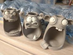 three clay shoes with faces on them sitting on a shelf