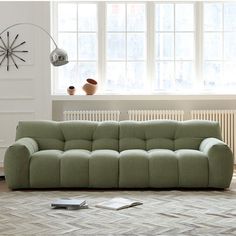 a green couch sitting on top of a wooden floor next to a white radiator