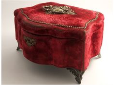 a red velvet covered box with gold trimmings on the top and bottom, sitting in front of a white background