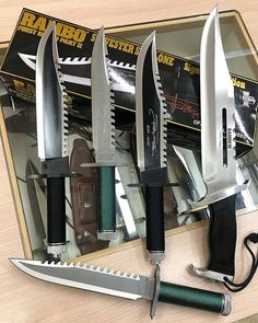 five knives are in a box on a table with other knifes and sheaths