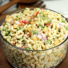 a bowl filled with macaroni salad on top of a wooden table