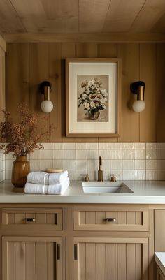 a bathroom with wood paneling and white counter tops, two framed pictures on the wall