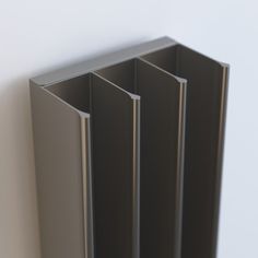 the corner section of a wall with three metal sections on it's side, in front of a white wall