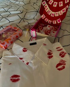 the shirt has lipstick prints on it and is next to a box with some other items