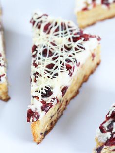 several pieces of cake with white icing and cranberry toppings