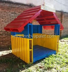 an outdoor play structure with a red roof and blue bottom, in front of a brick wall