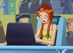 a woman sitting in front of a laptop computer on top of a blue desk next to other people