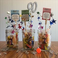 three glass jars filled with candy and confetti on top of a wooden table