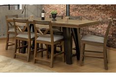 a wooden table with four chairs and a vase on top of it in front of a brick wall