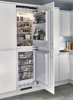 an open refrigerator in a kitchen with white cabinets