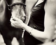 a black and white photo of a woman petting a horse