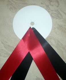 two red black and white ribbons are on top of a table cloth with a disc in the background