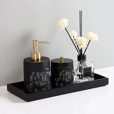 black and white bathroom accessories with flowers in vases on the counter next to it