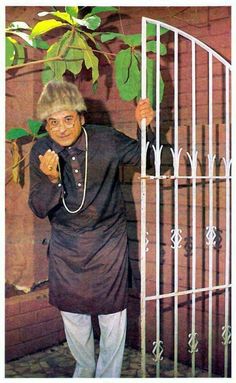 an old woman standing in front of a gate with her hand on the top of it