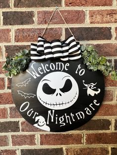 a welcome to our nightmares sign hanging on a brick wall