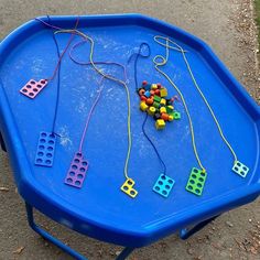 a blue table topped with lots of different colored beads and string on top of it