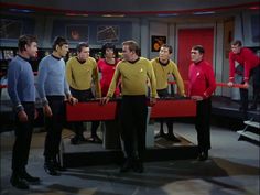 the crew of star trek standing in front of a table with two red trays on it