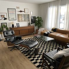 a living room with black and white checkered rug, brown leather couches and chairs