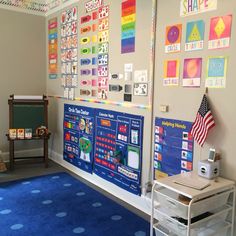 a classroom with blue carpet and various bulletin boards on the wall, including an american flag