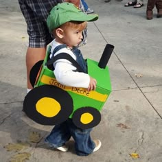 a little boy in a green tractor costume with his name on the box and hat