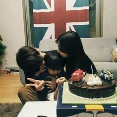 three people sitting on a couch in front of a cake with the flag of great britain behind them