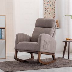 a rocking chair in a living room with a rug on the floor and bookshelf behind it