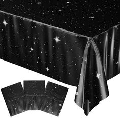 a black tablecloth with white stars on it and two matching napkins to the side